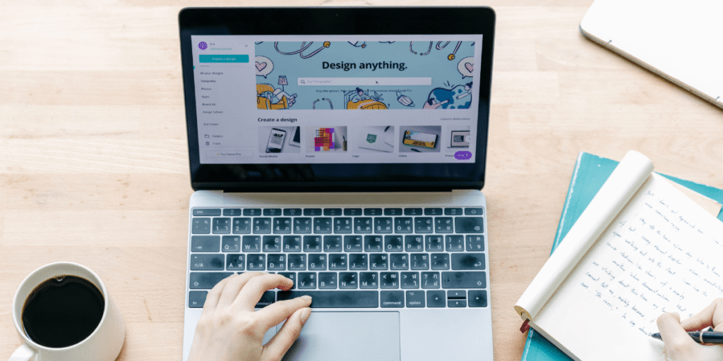 Person on laptop, with cup of coffee and notepad